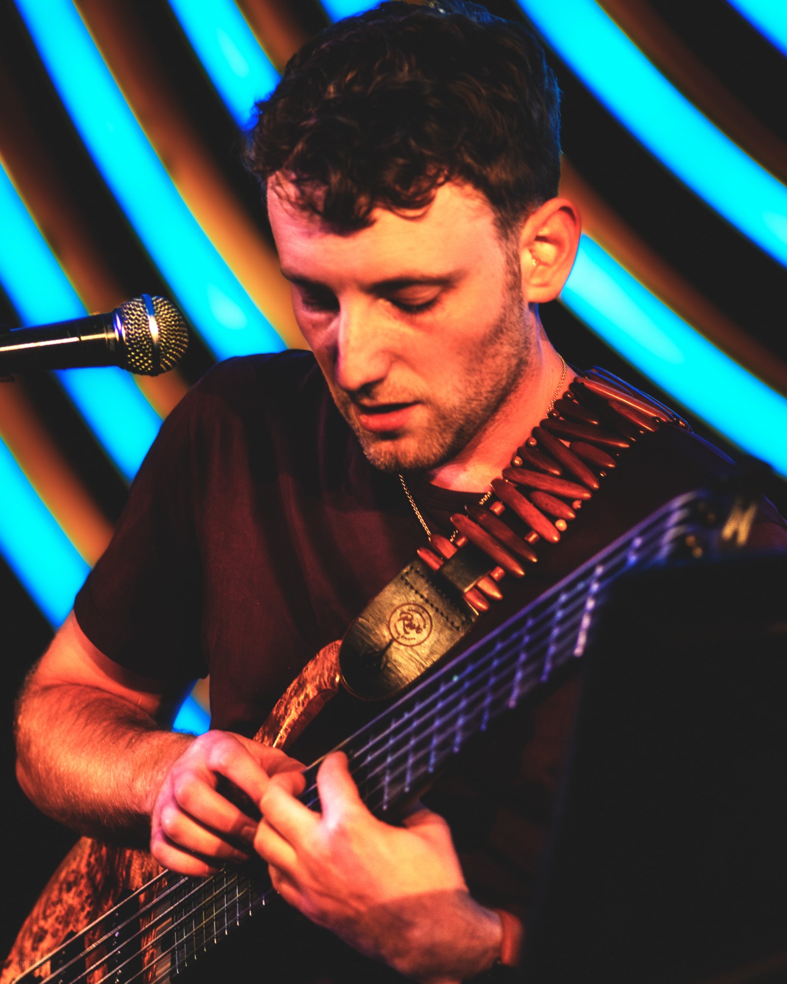 Jordan Lovinger playing six-string bass in warm stage light